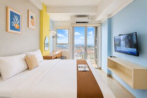 A modern hotel room with a large bed, a desk, a television, and a view of the city through the window. - Attractive And Stylish Studio At Apartment Poris 88 (Tangerang)