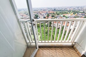 Ein Balkon mit Blick auf ein Wohngebiet, darunter Häuser und eine Kirche mit einer grünen Kuppel.