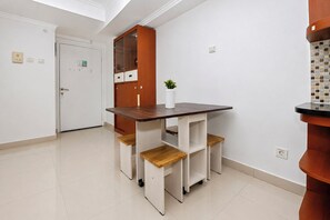 A compact kitchen with a wooden table, built-in shelves, and a white door. - Roomy Good Location 2Br At Apartment The Wave Kuningan (Jakarta)