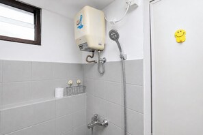A bathroom with a shower, toilet paper, and a smiley face decoration. - Tranquil And Modern Studio At Apartment Kebagusan City (Jakarta)