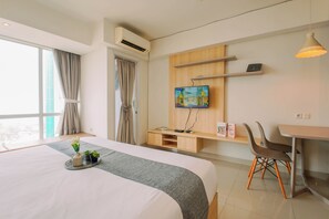 Ein modernes Hotelzimmer mit einem großen Bett, einem Schreibtisch, einem Fernseher und einem Fenster mit Vorhängen.