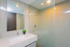 Ein modernes Badezimmer mit einem großen Spiegel, einem Waschbecken und einer Dusche.