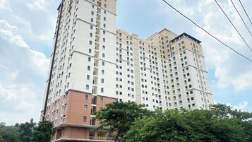 Un edificio residencial de varios pisos con balcones, entrada protegida y zona verde circundante.
