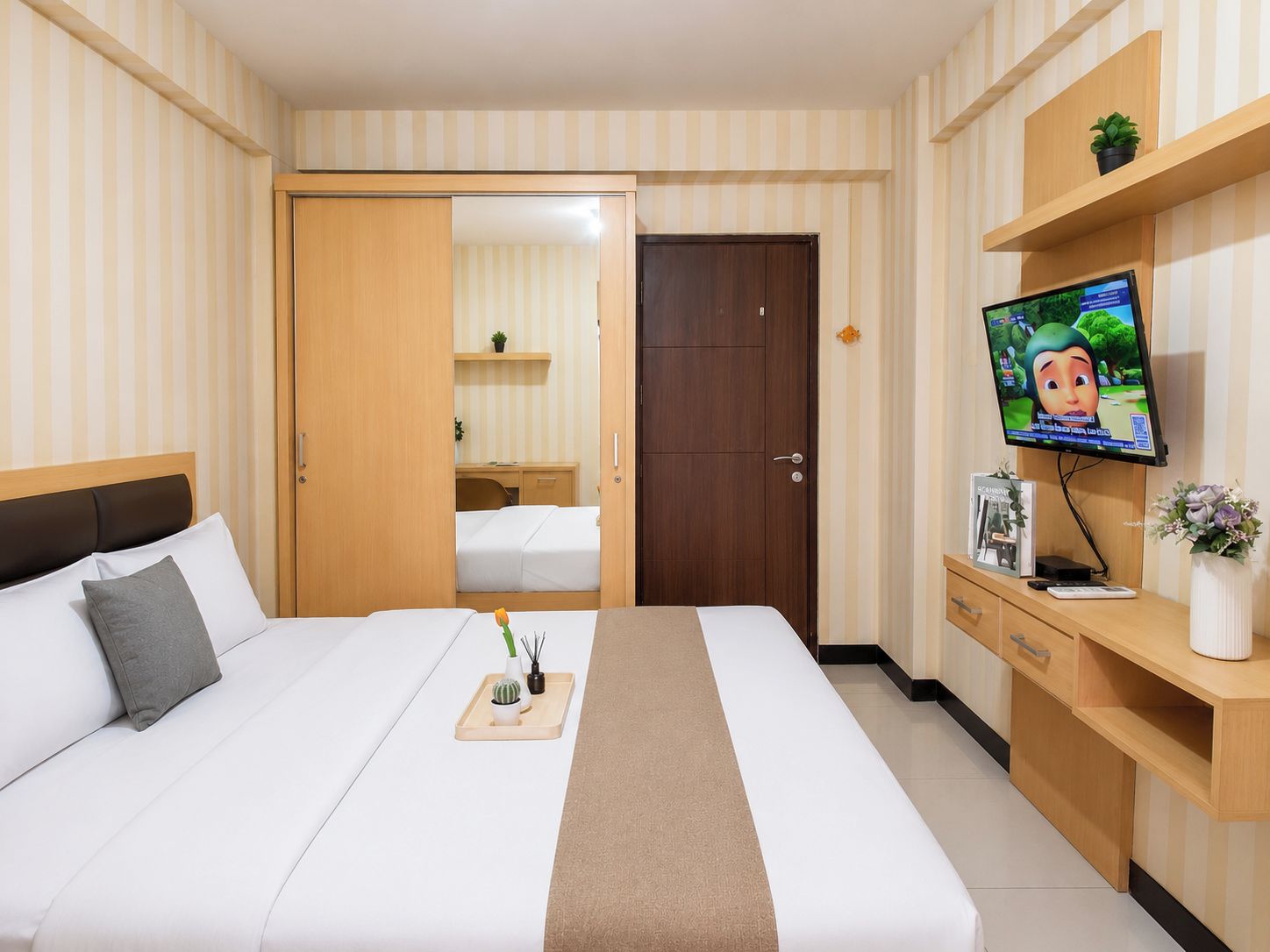 Habitación de hotel con cama, mesita de noche, televisión y escritorio con silla.