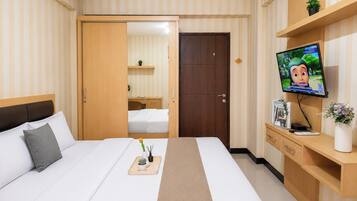 Habitación de hotel con cama, mesita de noche, televisión y escritorio con silla.