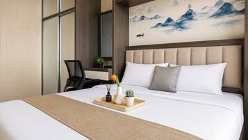 A hotel room with a large bed, a desk, and a painting of mountains.