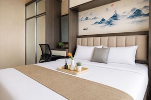 A hotel room with a large bed, a desk, and a painting of mountains. - Homey And Warm 1Br At Apartment Vasanta Innopark (Cikarang)