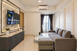 A modern living room with a sofa, a coffee table, and a TV mounted on a marble wall. - Lavish And Elegant 2Br Apartment Meikarta District 1 (Cikarang)