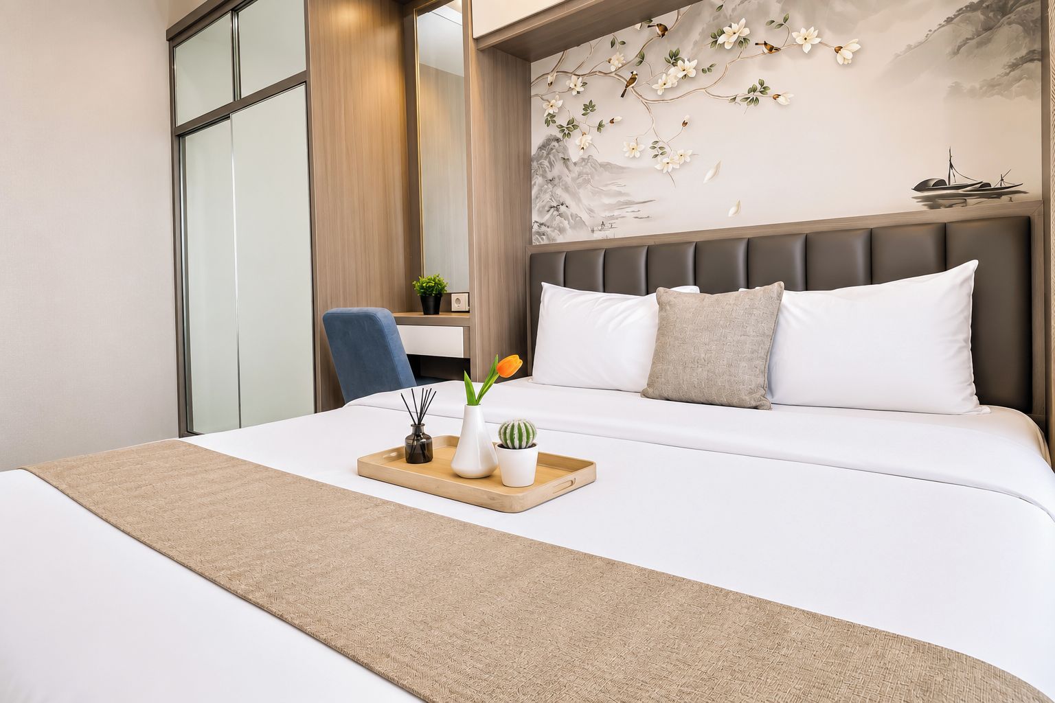 A hotel room with a bed, a desk, and a wall with a floral mural.