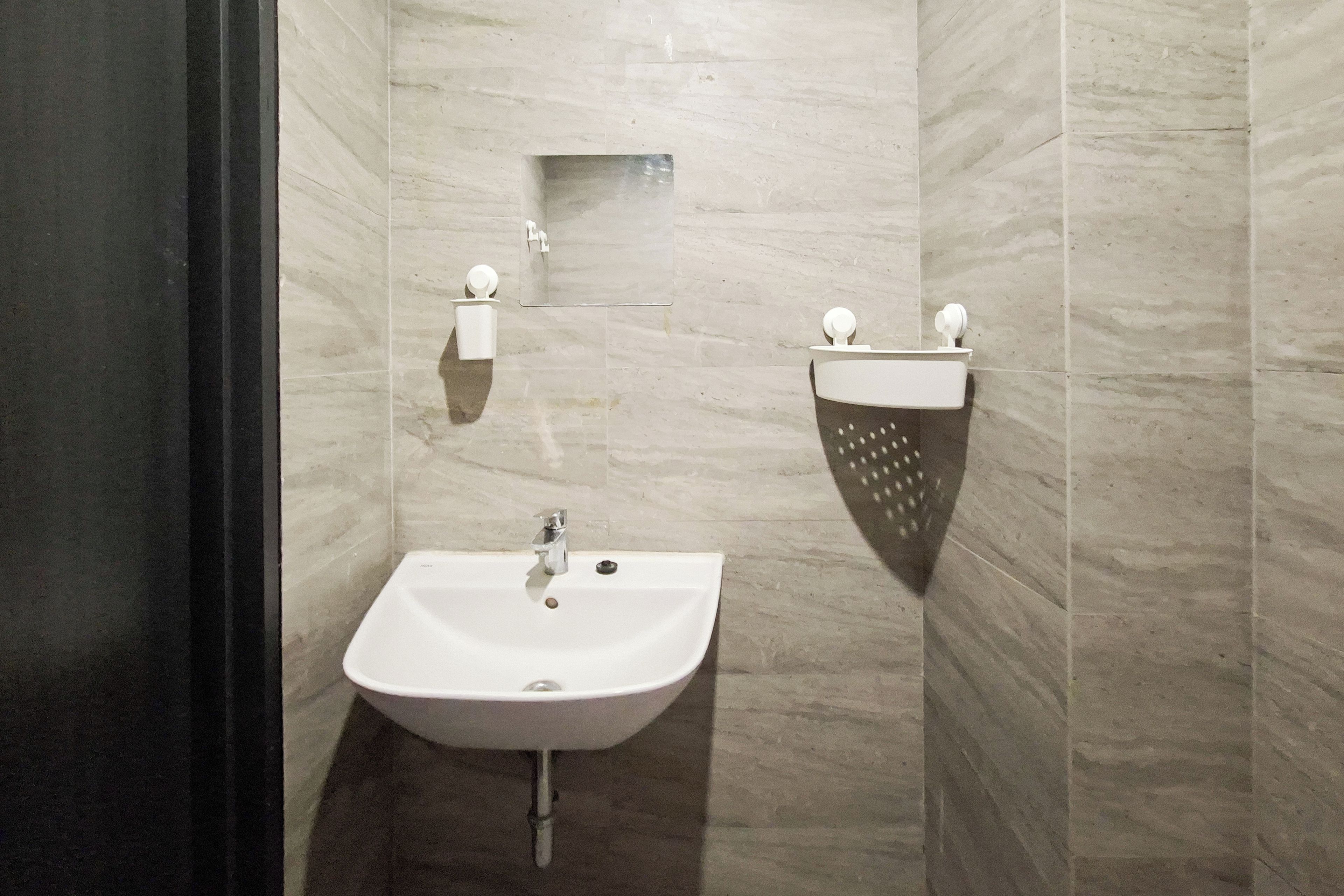 Une salle de bain avec un lavabo blanc, un miroir et deux distributeurs de serviettes.