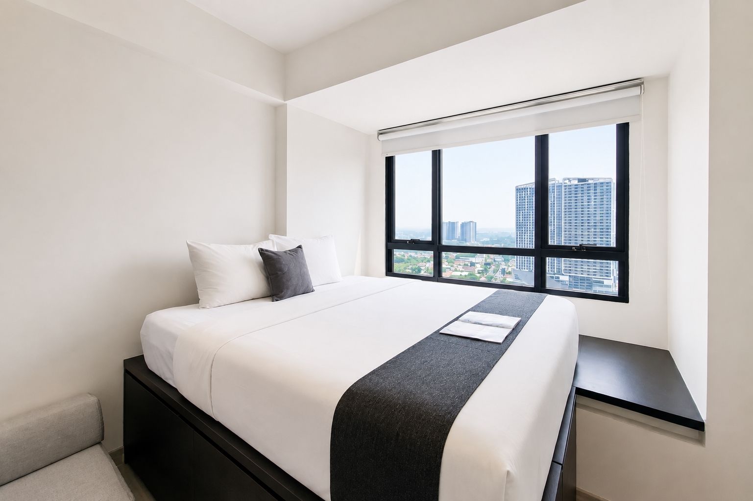 Una habitación de hotel moderna con una cama grande, vistas de la ciudad a través de una ventana y una mesita de noche negra.