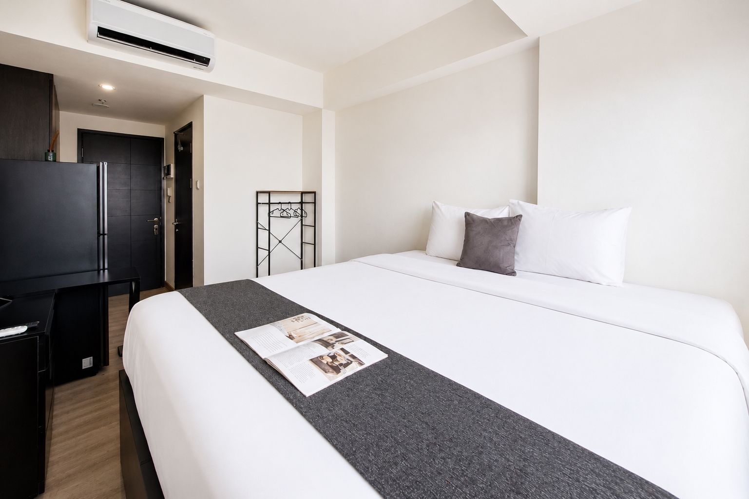 Una habitación de hotel con cama, escritorio, televisor y armario.