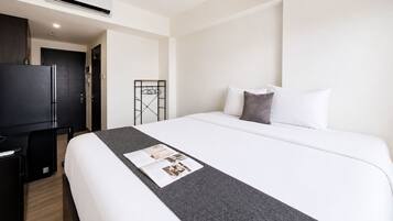 Una habitación de hotel con cama, escritorio, televisor y armario.