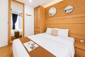 Ett hotellrum med en säng, en väggpanel i trä, två runda speglar och ett fönster med gardiner.