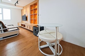 A modern living room with a sofa, a glass-top table, and built-in shelving. - Appealing 1Br At Apartment Urbantown Serpong (Tangerang)