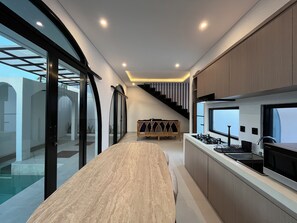 A modern kitchen with a central island, built-in appliances, and a staircase leading to an upper level. - 2Br Mediterranean Private Pool Villa Nusa Dua (Bali)