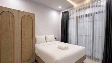 Een moderne hotelkamer met een groot bed, een inloopkast met geweven motief en dunne gordijnen.