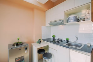 A compact kitchen with a GEA refrigerator, a built-in stove, a sink, and two stools.
