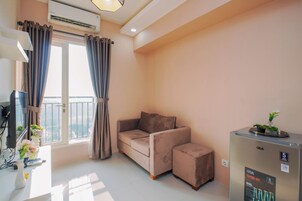 A modern living room with a sofa, a small table with a vase, and a refrigerator.