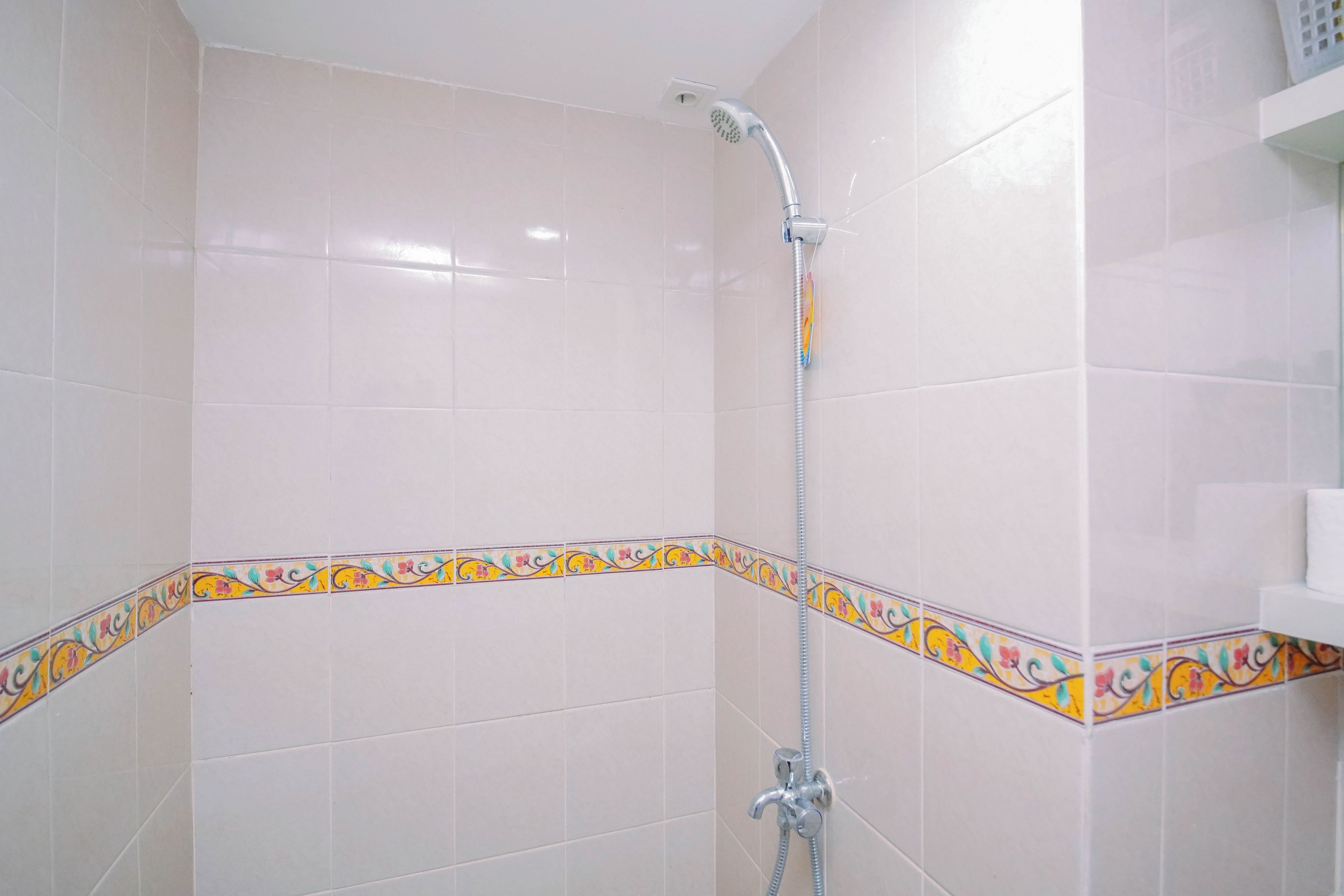 A shower area with a showerhead, a handheld shower attachment, and a wall-mounted faucet.
