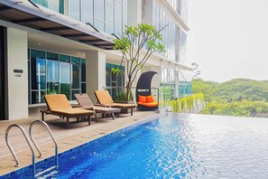 A modern hotel with a rooftop infinity pool, lounge chairs, and a view of the surrounding landscape. - Affordable Neat 1Br At Apartment Brooklyn Alam Sutera (Tangerang)