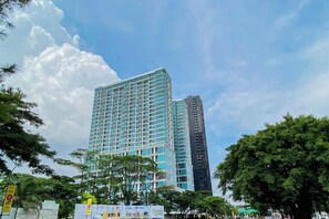 A high-rise building with a modern architectural design, featuring a grid of windows and a prominent corner structure. - Affordable Neat 1Br At Apartment Brooklyn Alam Sutera (Tangerang)