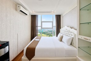 A hotel room with a large bed, a view of the city, and an air conditioning unit on the wall. - Affordable Neat 1Br At Apartment Brooklyn Alam Sutera (Tangerang)