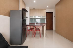 Een moderne keuken met een koelkast, een eettafel met stoelen en een houten kast.