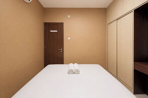 A hotel room with a bed, a wardrobe, and a door. - Spacious And Warm 2Br At Apartment Vivo (Depok)