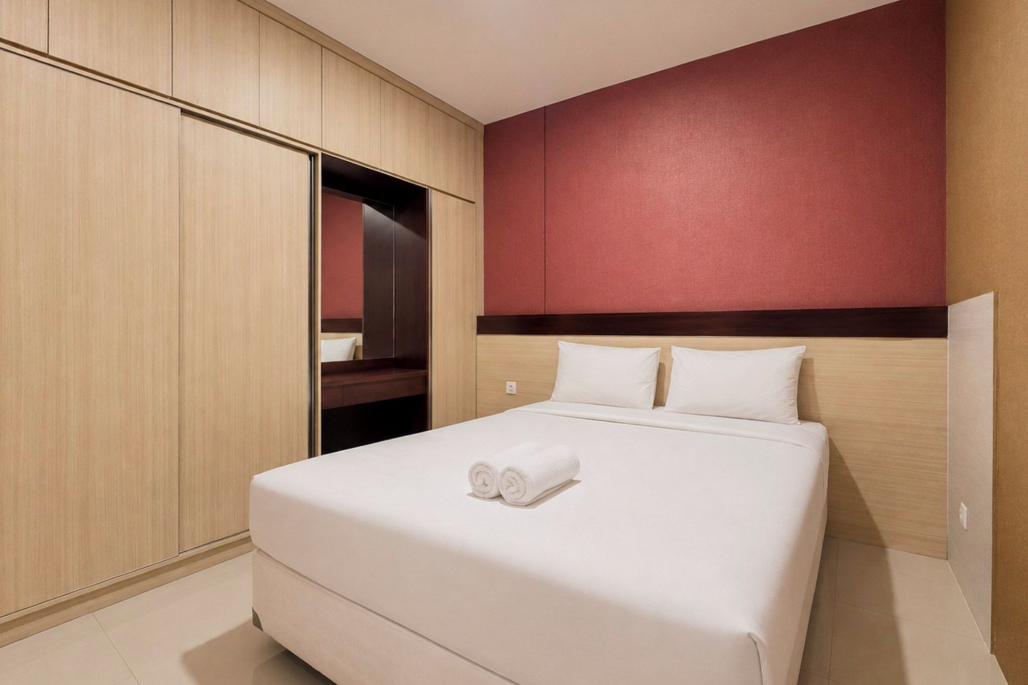 A hotel room with a bed, a wardrobe, and a mirror.
