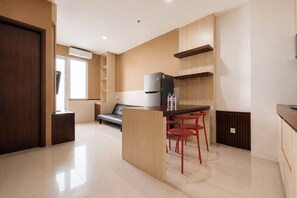 A modern kitchen with a central island, red bar stools, and a built-in refrigerator. - Spacious And Warm 2Br At Apartment Vivo (Depok)