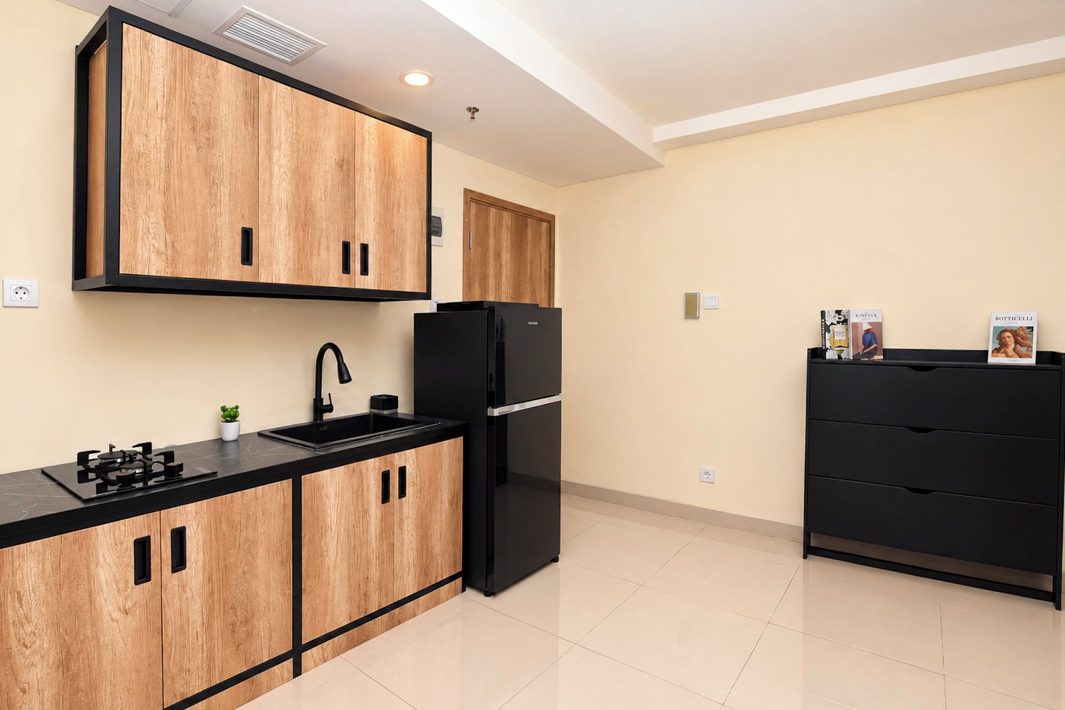 A modern kitchen with wooden cabinets, a black refrigerator, and a black countertop.