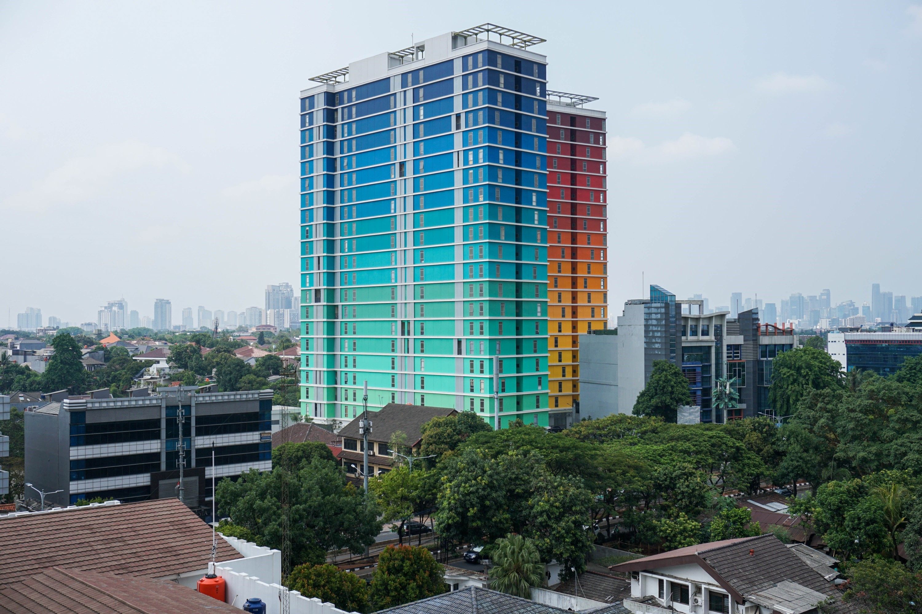A multi-story building with a grid-like facade, surrounded by trees and other buildings.