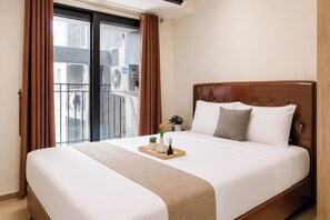 A hotel room with a bed, a window with curtains, a small table with a tray, and a potted plant. - Warm And Peaceful 2Br At Apartment Meikarta District 1 (Cikarang)