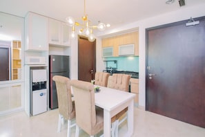 A modern kitchen with a dining area, including a refrigerator, microwave, and a water dispenser. - Luxurious And Deluxe 2Br At Setiabudi Skygarden Apartment (Jakarta)