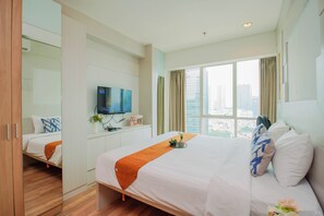 A hotel room with a large bed, a TV, a window with curtains, and a view of the city. - Luxurious And Deluxe 2Br At Setiabudi Skygarden Apartment (Jakarta)