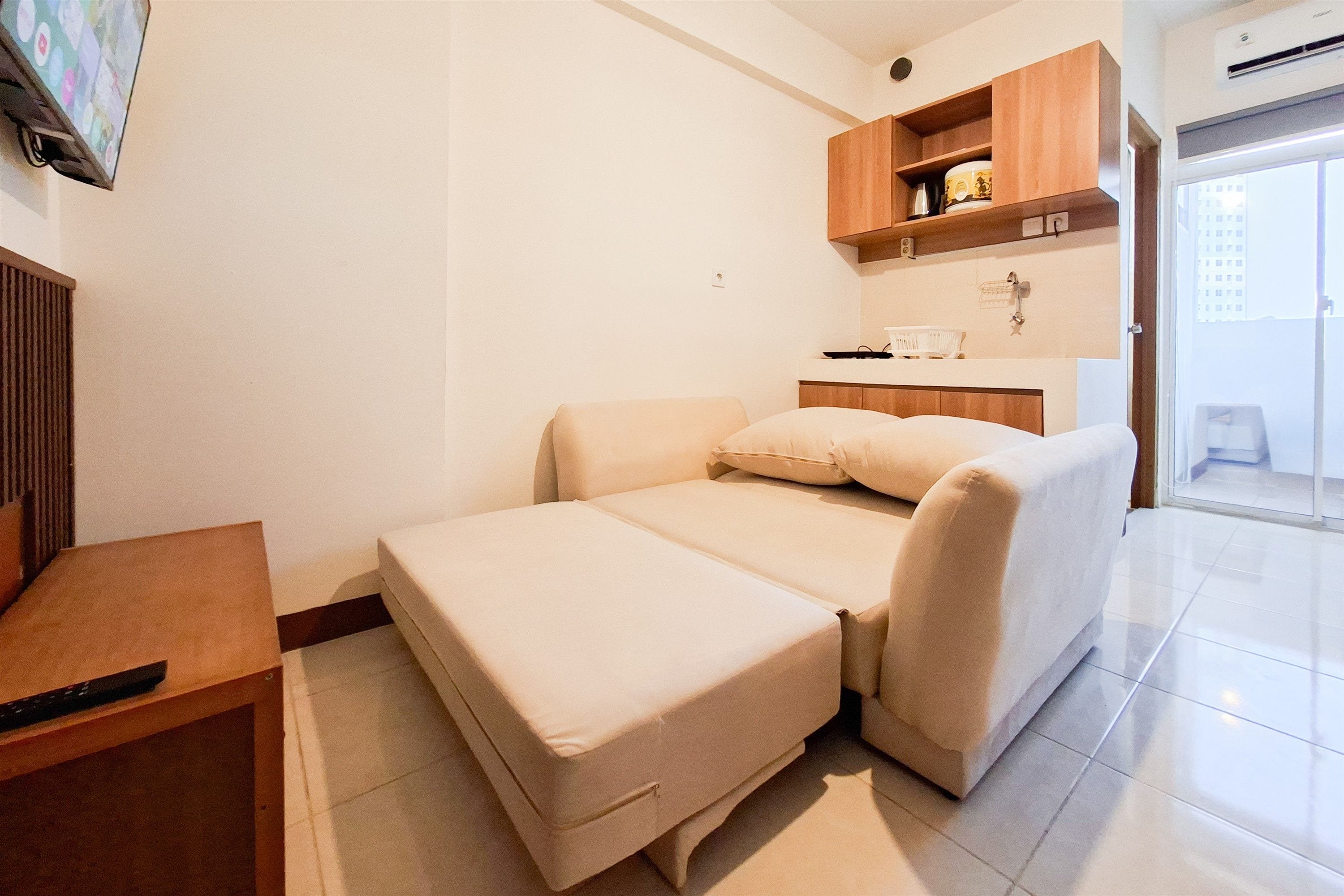 Una habitación compacta con cama, una mesita, kitchenette y baño.