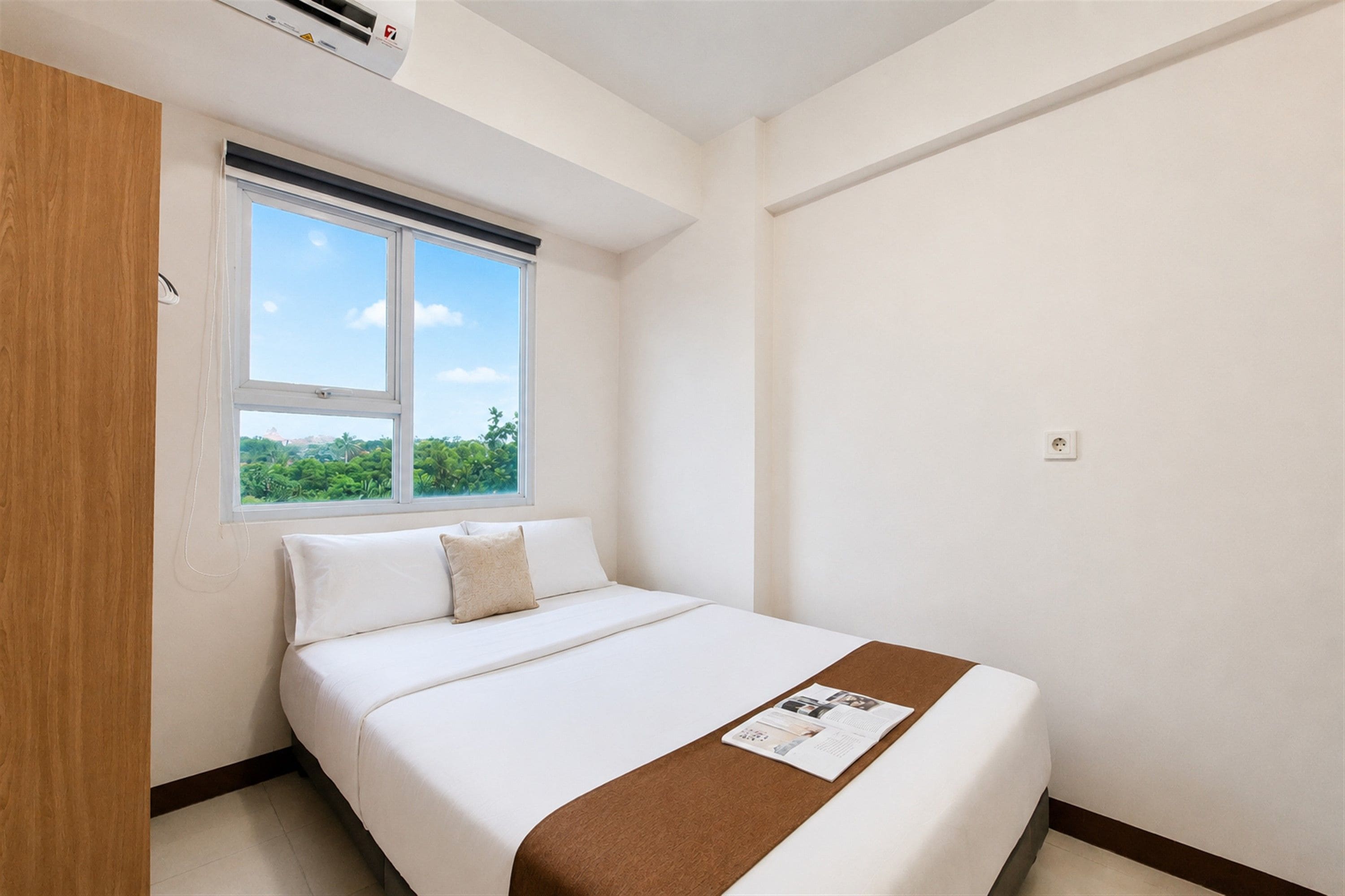 Una habitación de hotel con una cama, un ventanal con vistas y un armario de madera.