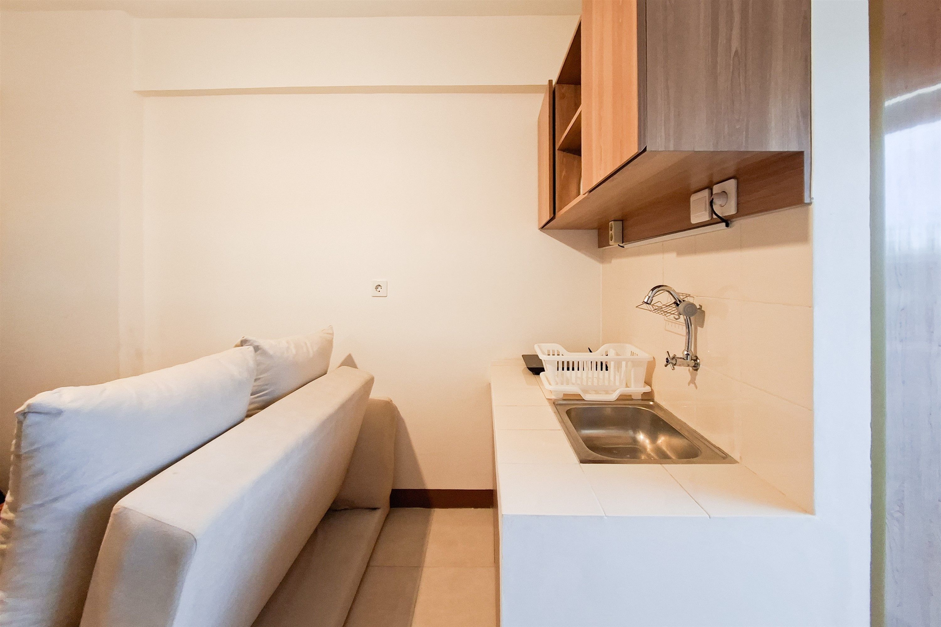 Una kitchenette compacta con un lavamanos empotrado, una pequeña encimera y un armario de madera encima.
