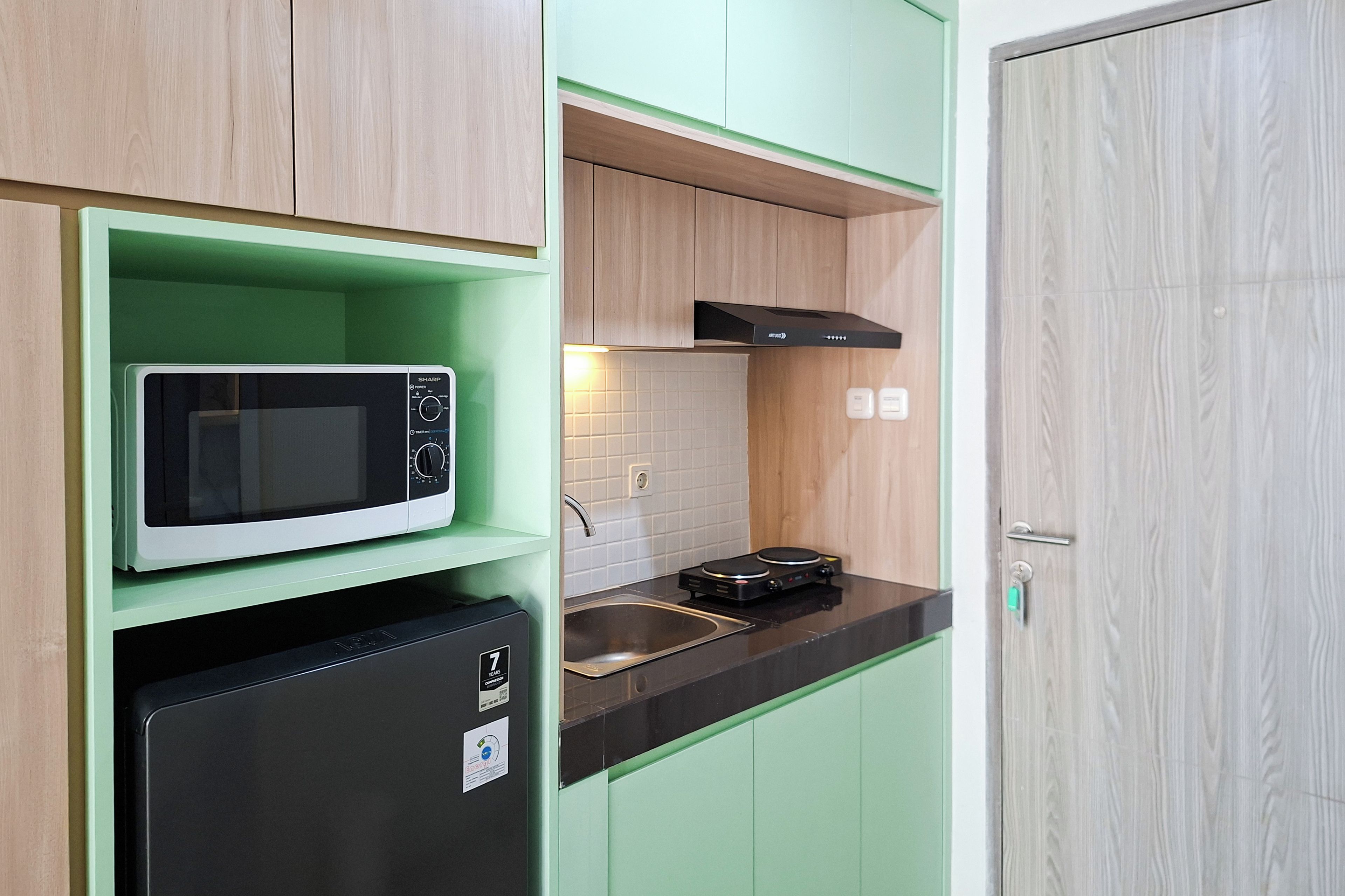 A compact kitchen with a microwave, a small refrigerator, and a stove.