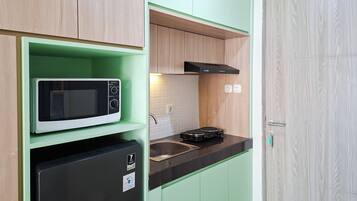 A compact kitchen with a microwave, a small refrigerator, and a stove.
