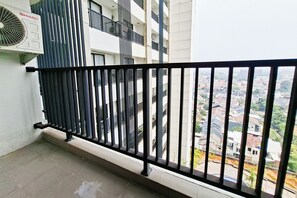 Ein Balkon mit schwarzem Metallgeländer, einer weißen Wand und Blick auf eine Wohngegend.