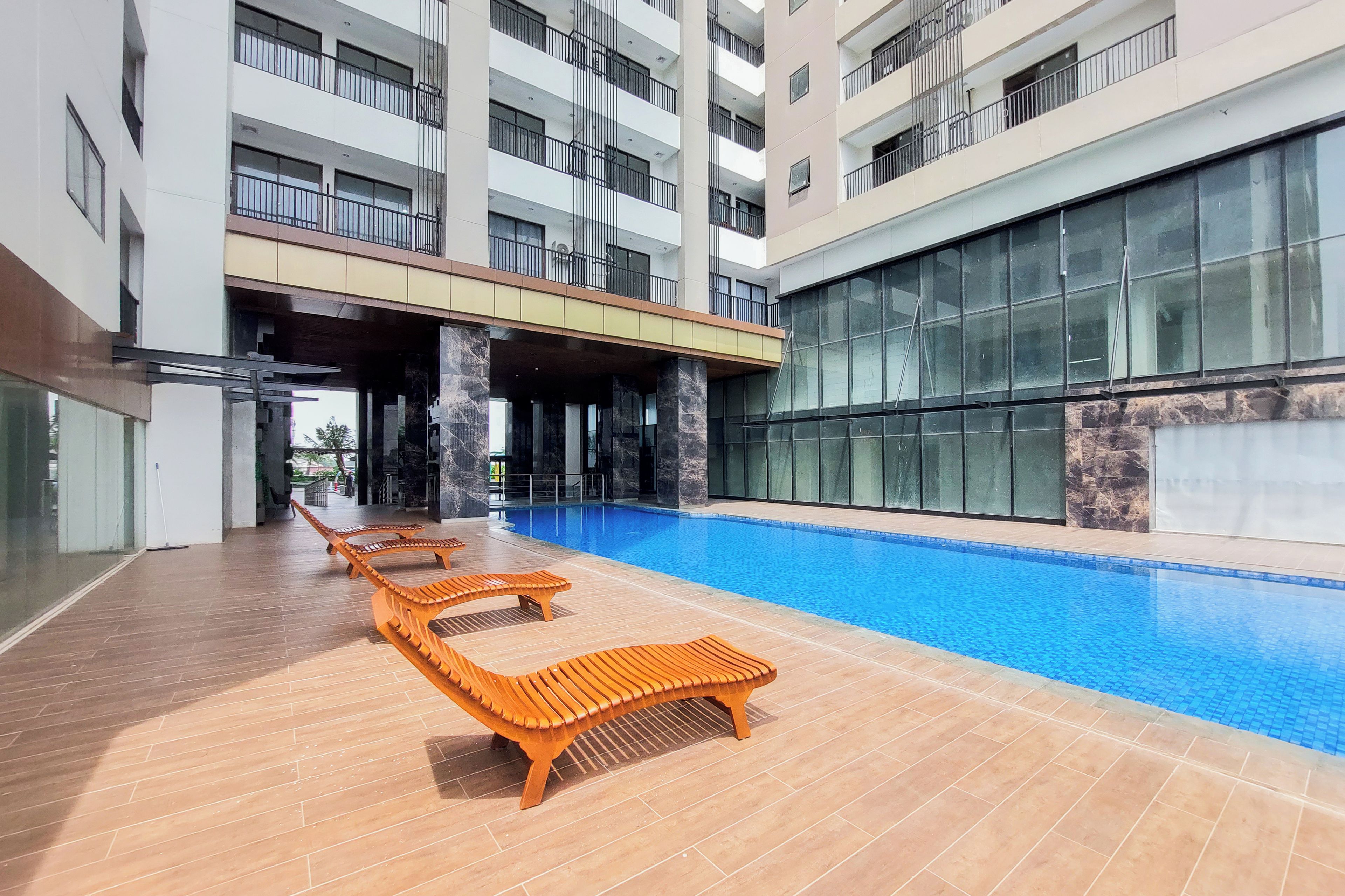 Un área de piscina con sillas de descanso y un edificio moderno al fondo.