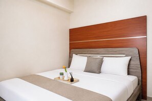Une chambre d’hôtel avec un lit, une table de chevet et une petite table d’appoint.