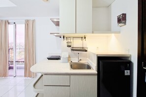 A compact kitchen with a built-in dishwasher, a sink, and a small countertop. - Bright And Cozy Studio At Apartment Casa De Parco (Pagedangan)