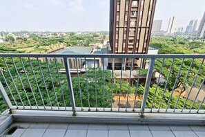 A balcony with a metal railing overlooking a residential area with trees and buildings. - Bright And Cozy Studio At Apartment Casa De Parco (Pagedangan)
