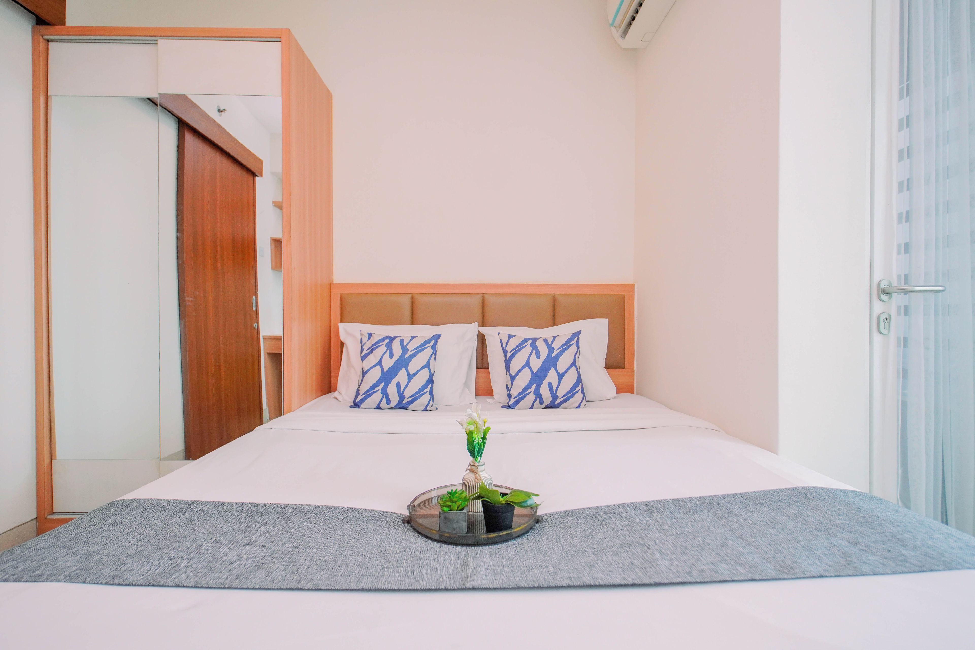Una habitación de hotel con una cama, dos almohadas, una mesita de noche y una ventana.