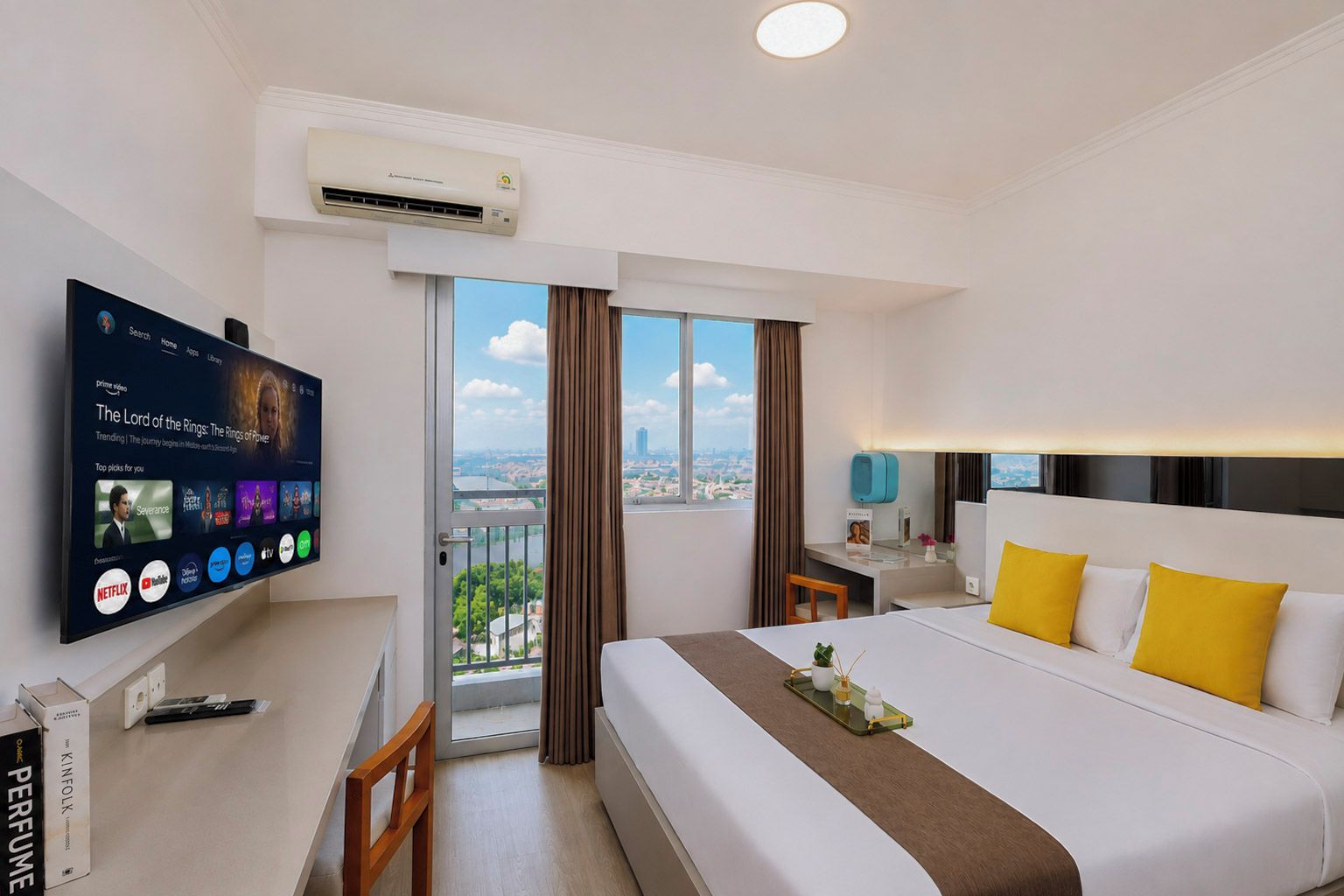 Une chambre d’hôtel avec un grand lit, un bureau, un téléviseur fixé au mur et une vue sur la ville par la fenêtre.