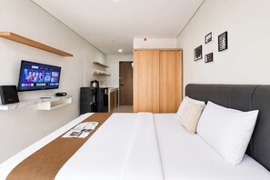 Une chambre d’hôtel équipée d’un lit, d’une télévision, d’un minibar, d’un bureau et d’une armoire.