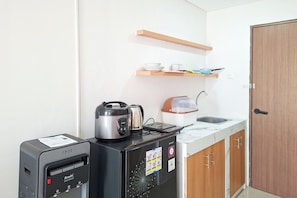 Une cuisine compacte équipée d’une machine à café, d’un cuiseur à riz et d’un petit réfrigérateur.